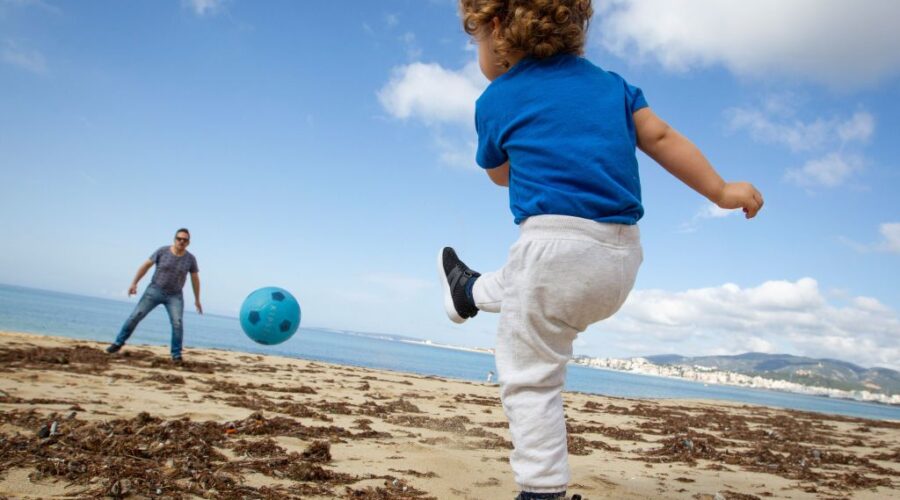 TOPSHOT - A child plays footbal with his father at Can Pere Antoni Beach in Palma de Mallorca, on April 26, 2020 during a national lockdown to prevent the spread of the COVID-19 disease. - After six weeks stuck at home, Spain's children were being allowed out today to run, play or go for a walk as the government eased one of the world's toughest coronavirus lockdowns. Spain is one of the hardest hit countries, with a death toll running a more than 23,000 to put it behind only the United States and Italy despite stringent restrictions imposed from March 14, including keeping all children indoors. Today, with their scooters, tricycles or in prams, the children accompanied by their parents came out onto largely deserted streets. (Photo by JAIME REINA / AFP) (Photo by JAIME REINA/AFP via Getty Images)
