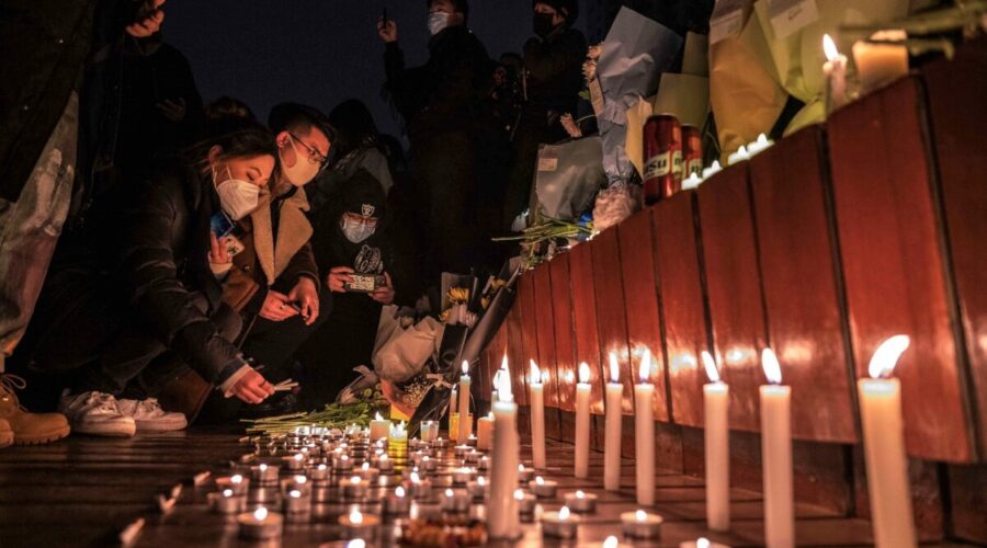 Protestující zapalují svíčky u památníku během protestu proti přísným opatřením nulového COVID režimu v Pekingu 27. listopadu 2022. (Kevin Frayer/Getty Images)