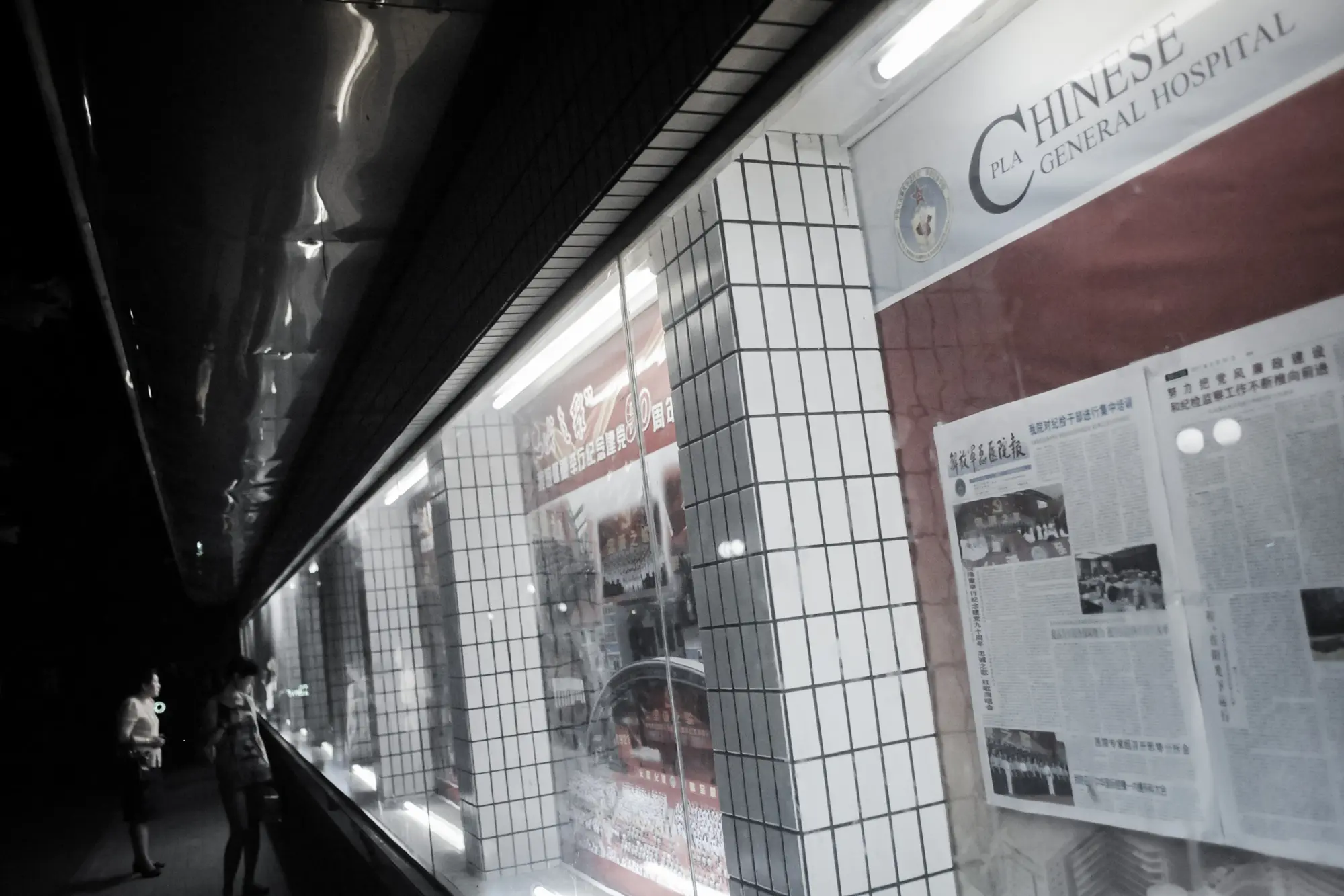 Lidé si prohlížejí články a fotografie na nástěnce v areálu nemocnice 301, kde často čerpají zdravotní péči nejvyšší čínští představitelé, Peking, 6. července 2011. (Goh Chai Hin / AFP via Getty Images)