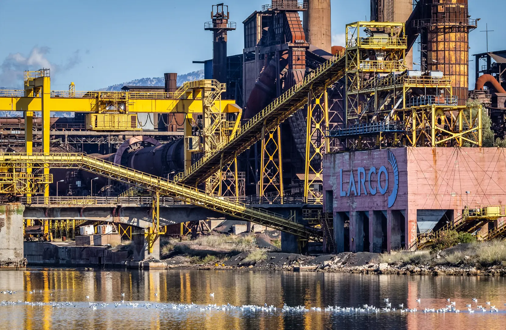 (Horní snímek) Opuštěná bývalá niklová tavírna v Larymně v Řecku, dne 12. listopadu 2025. S opětovným rozšiřováním nadnárodních těžebních operací by rozsáhlé zásoby kritických surovin mohly z Řecka učinit významnou výrobní velmoc, zatímco Evropa usiluje o snížení závislosti na čínských dovozech. (Dolní snímek) Staré těžební zařízení poblíž rušného přístavu Lavrio v Řecku, dne 12. listopadu 2025. (John Fredricks / Epoch Times)