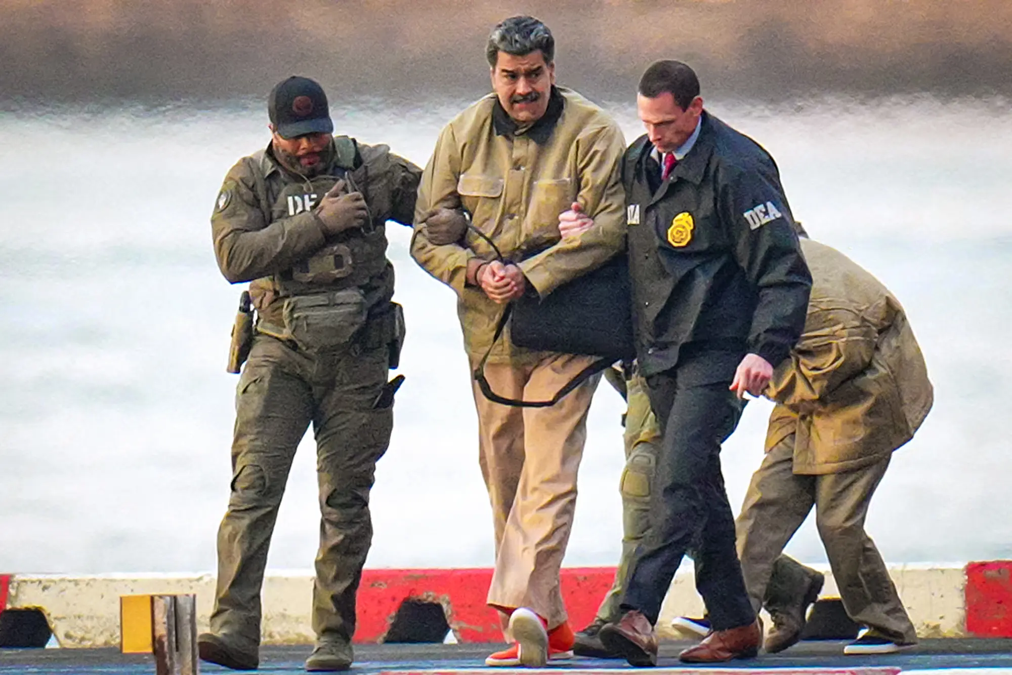 Nicolás Maduro a jeho manželka Cilia Floresová (vzadu) jsou po přistání na heliportu v New Yorku 5. ledna 2026 eskortováni federálními agenty do obrněného vozu směřujícího k federálnímu soudu. (XNY / Star Max / GC Images)