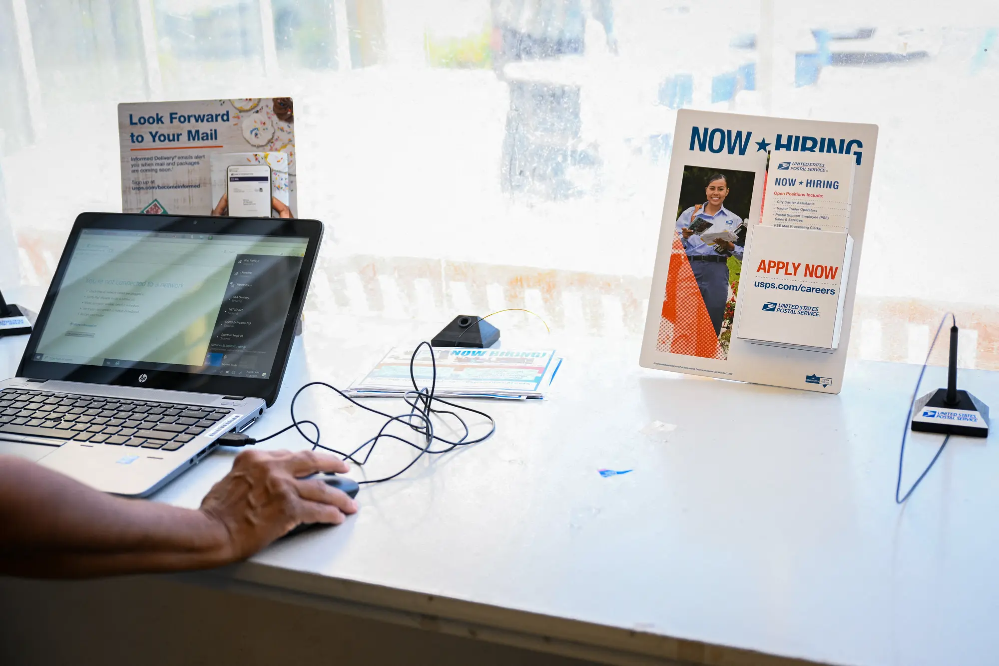 Zaměstnanec připravuje notebook pro podání žádosti během náborového veletrhu pro poštovní pracovníky v zařízení americké pošty v Inglewoodu v Kalifornii, 18. července 2022. (Patrick T. Fallon / AFP via Getty Images)