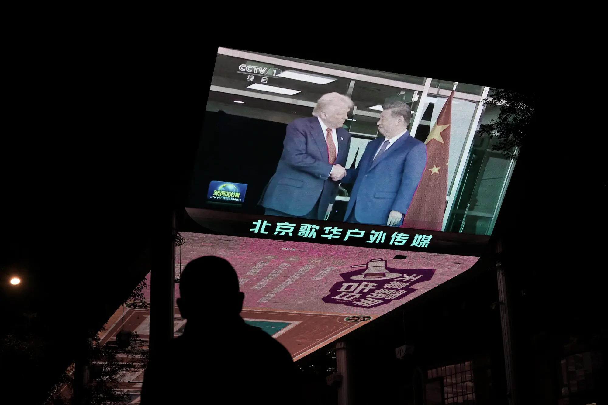 Zpravodajství o setkání amerického prezidenta Donalda Trumpa a čínského vůdce Xi Jinpinga v Jižní Koreji na televizní obrazovce u nákupního centra v Pekingu, 30. října 2025. (Adek Berry/AFP přes Getty Images).